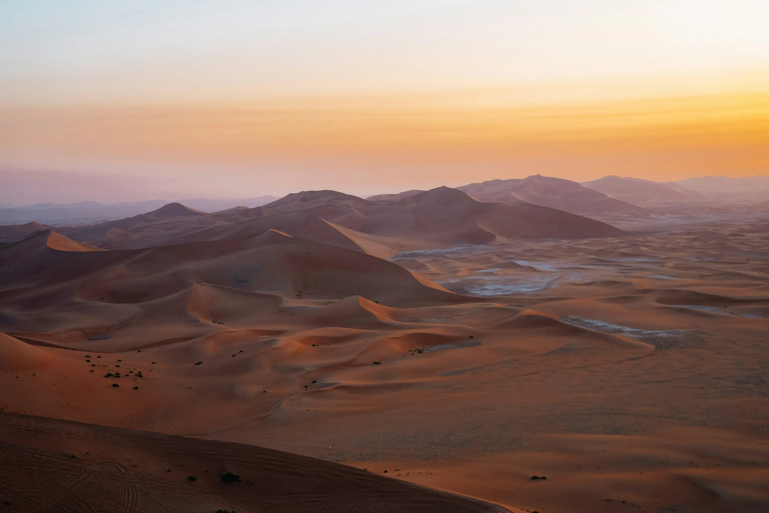 Dune ridges leading to a hazy skyline at sunset